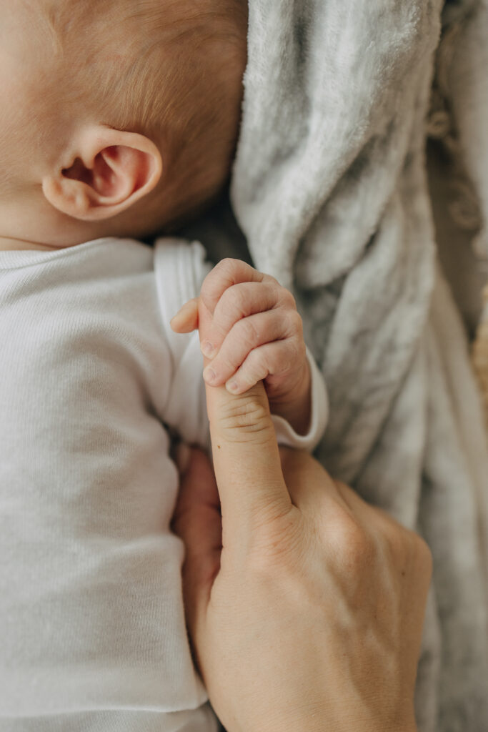 Neugeborenen Shooting zu Hause, wo das Baby Mamas Finger hält.